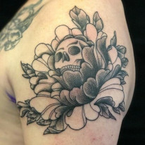 Skull in peonies tattoo done in black and grey.