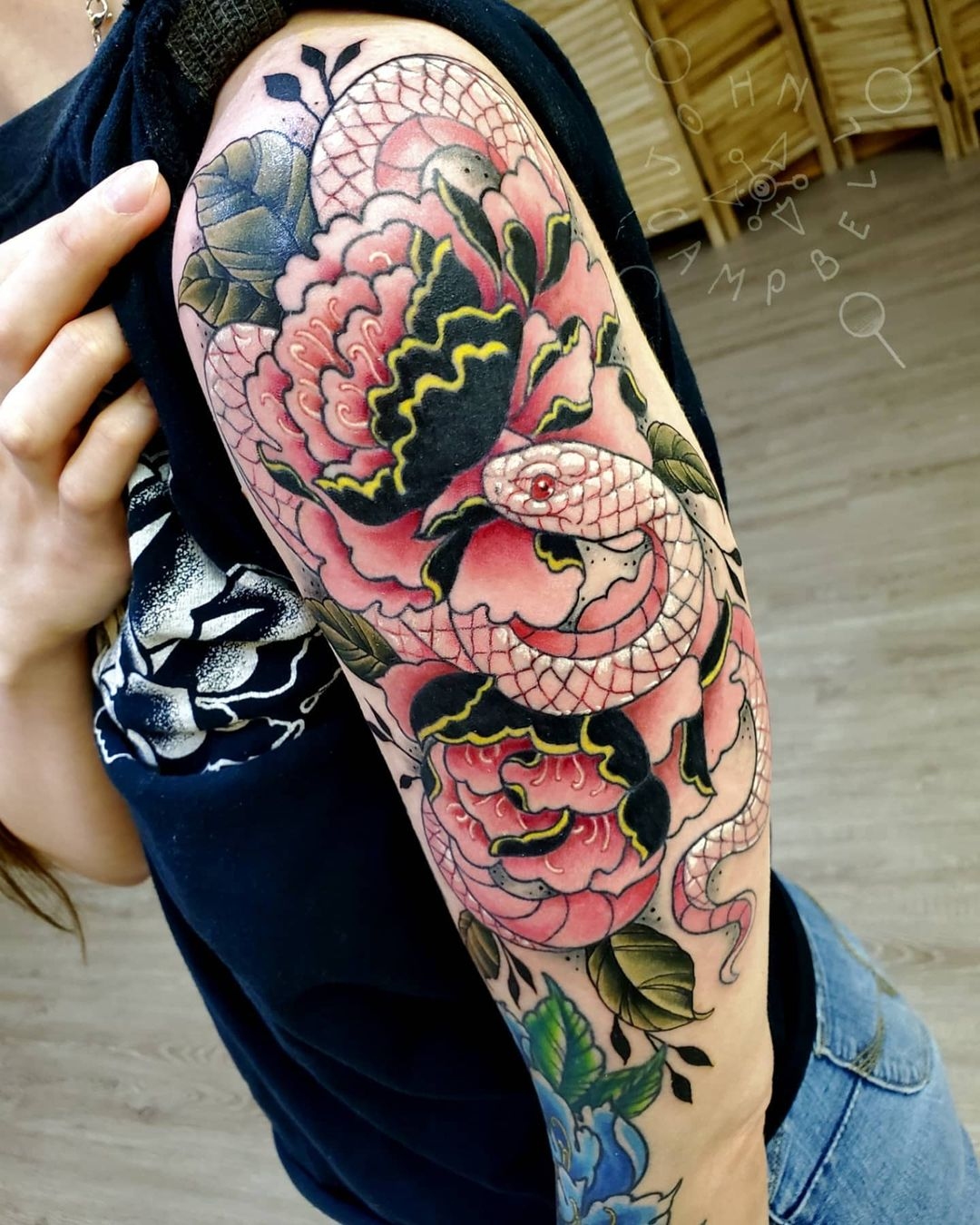 Tattoo of a snake with flowers by John Campbell at Sacred Mandala Studio tattoo parlor in Durham, NC.