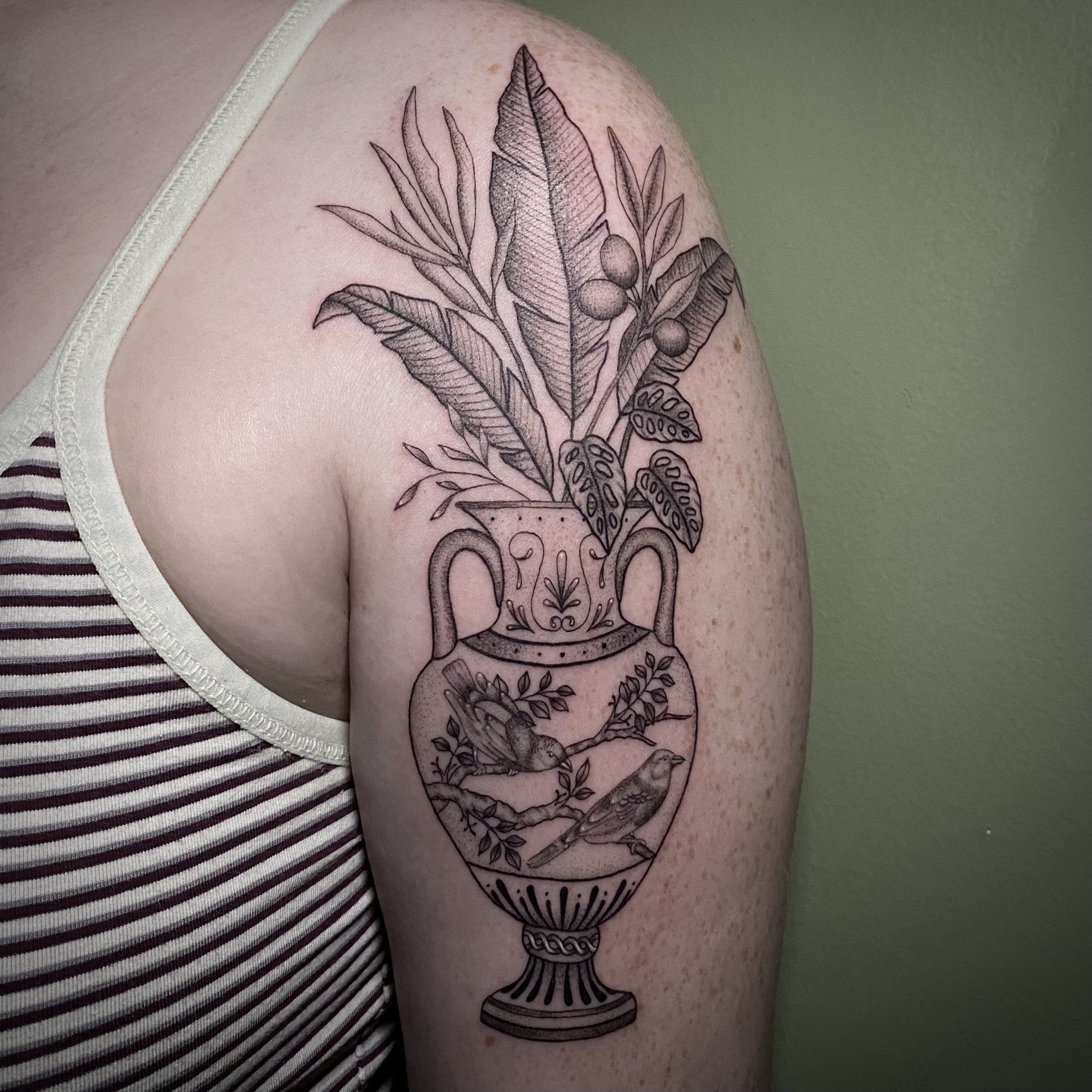 Fine line black and grey tattoo of a classical greek amphora filled with folliage tattooed by Sarah Cherney of Sacred Mandala Studio.
